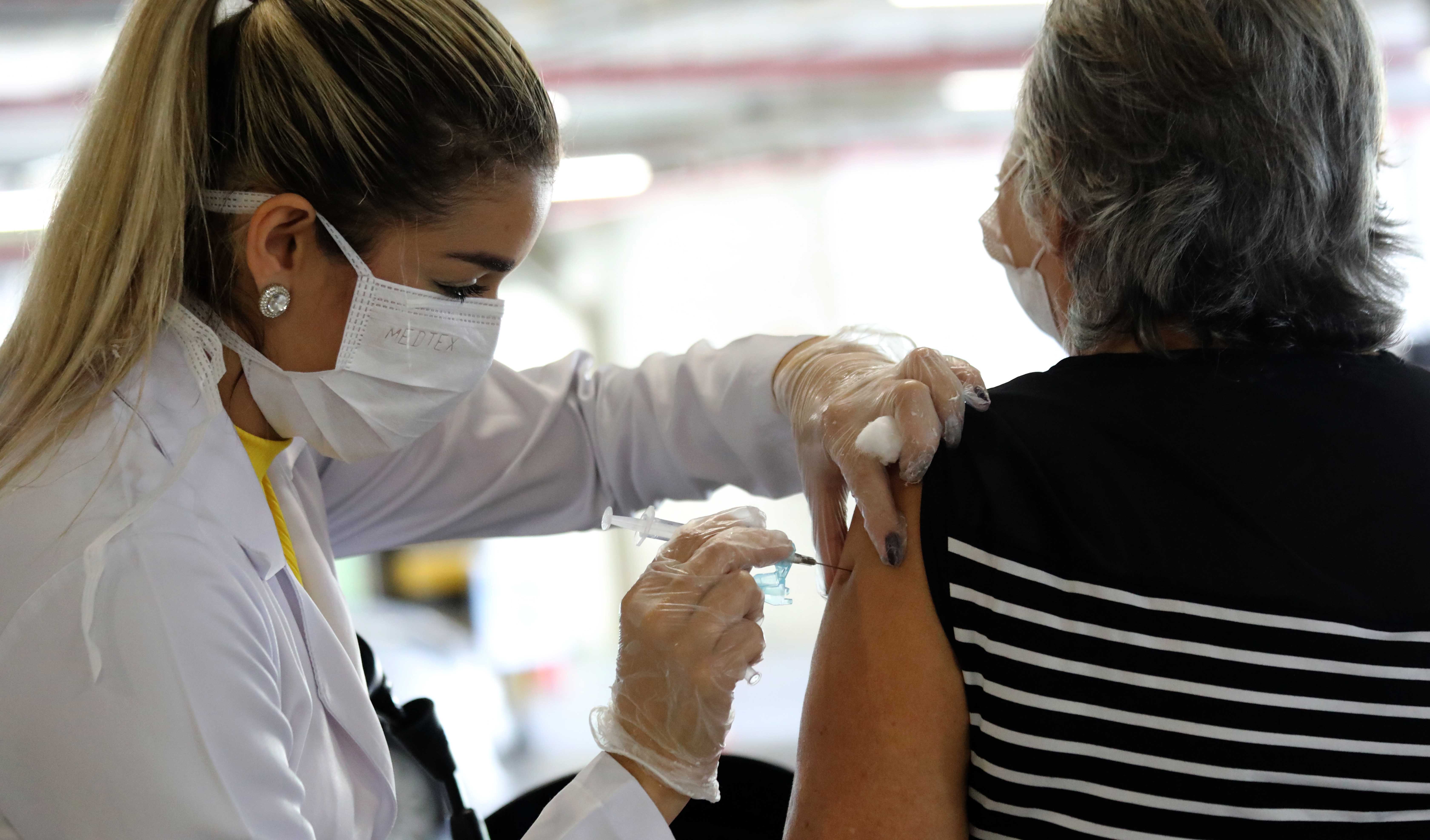 mulher profissional de saúde aplicando vacina em idosa de costas